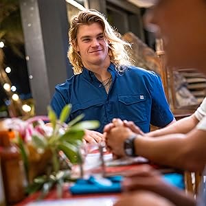 Man wears huk tide point button down shirt while at dinner with friends