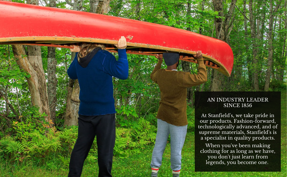 Two men carrying a canoe wearing a hoodie, henley, pants, hat, long johns