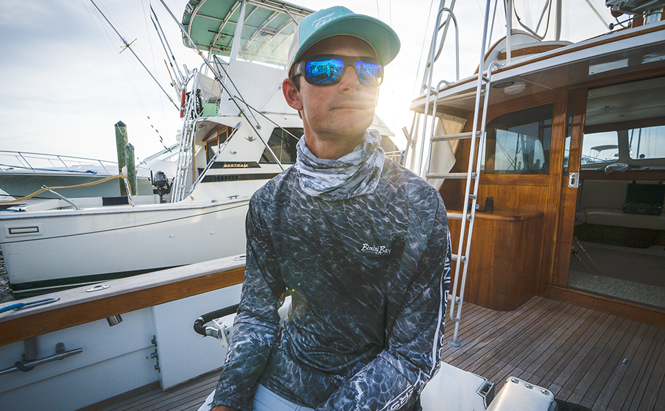 Bimini Bay Outfitters - Fisherman on boast with sun peaking out from behind him.